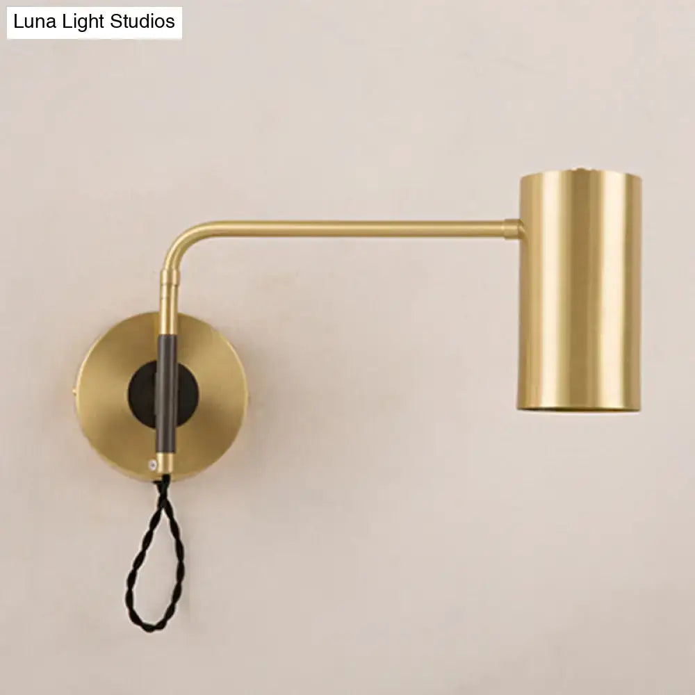 Modern black and brass wall lamp with curved arm, cylindrical head, and black braided cord for bedroom lighting fixture height