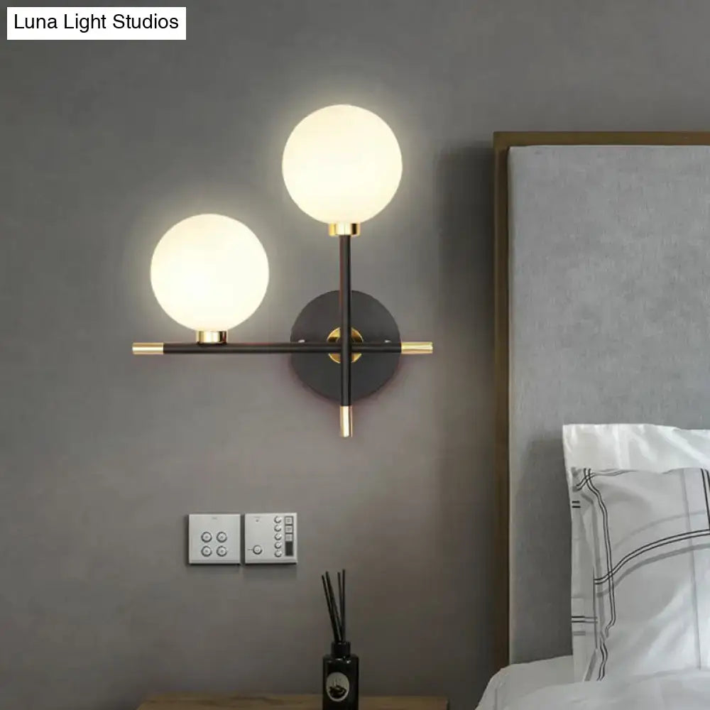Modern black and brass wall lamp with frosted glass ball globes and sleek metal frame as a ball bedside sconce