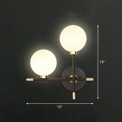 Modern black and brass wall lamp with two frosted glass ball shades and wall mounted light for bedside use
