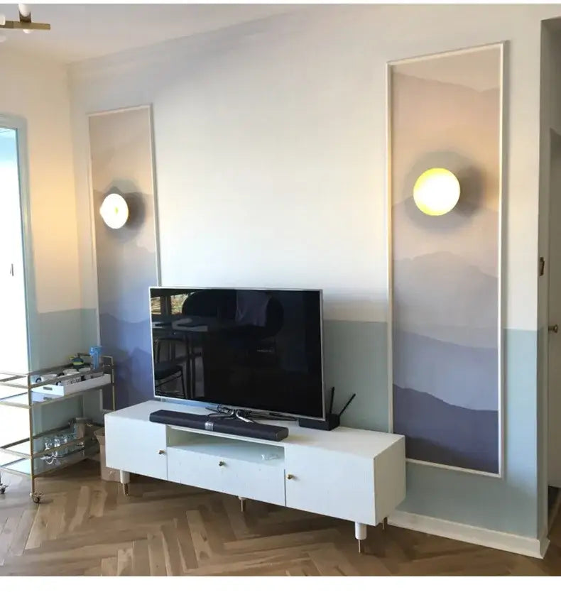 White minimalist tv stand with sleek legs and glass drawer fronts complementing decorbites golden glass wall light fixture