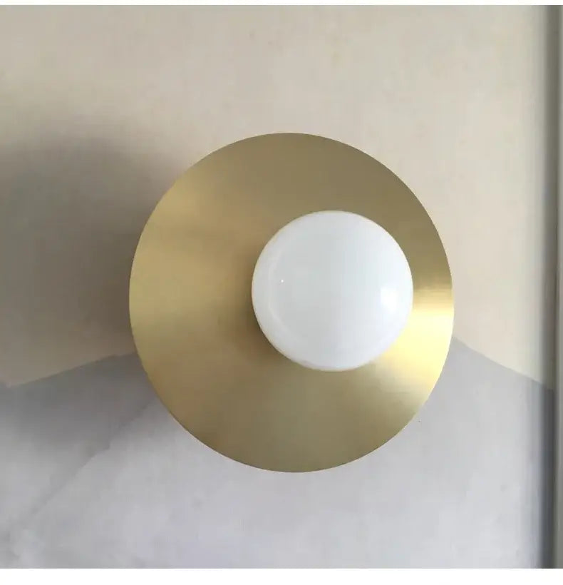 Modern black and brass glass ball wall light fixture with minimalist brass base and central white globe bulb by decorbites golden glass