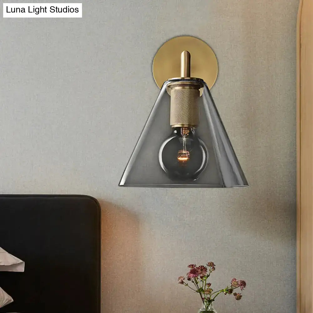 Modern wall light with brass finish, textured stem, gray glass cone shade, direct wired electric for bedroom use