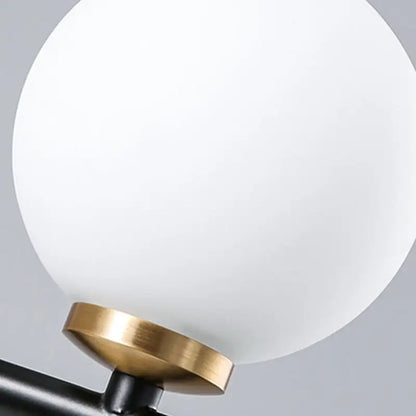 Modern black and brass linear chandelier featuring a spherical white glass frosted globe lampshade for dining room