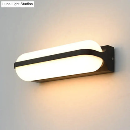 Modern black capsule flush wall sconce with a sleek oval diffuser providing warm white illumination as a wall-mounted lamp