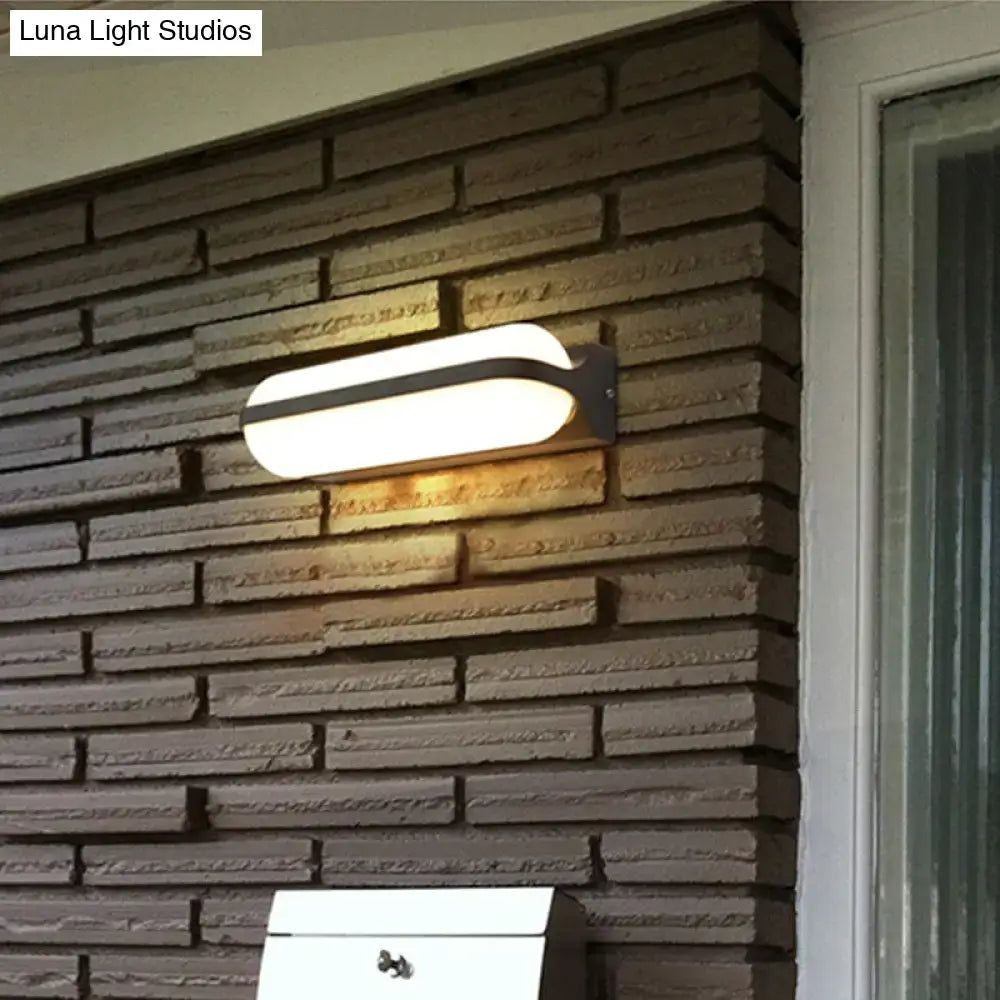 Modern black capsule flush wall sconce with sleek metal frame and frosted glass diffuser wall-mounted lamp on brick exterior