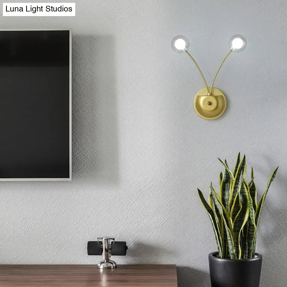 Modern black cast iron double globe wall sconce with gold-toned arms and clear glass globe bulbs in a 12 inches fixture