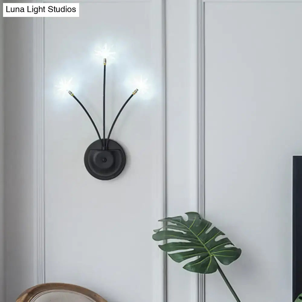 Modern black cast iron wall sconce with three curved arms and gold tips emits soft glow in living room light fixture inches tall