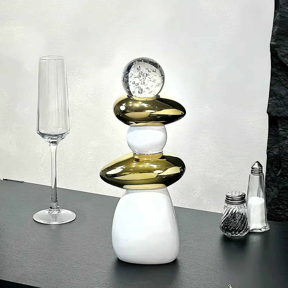 A modern black ceramic decorative crystal ball statue with stacked polished gold and white orbs and a clear glass bubble