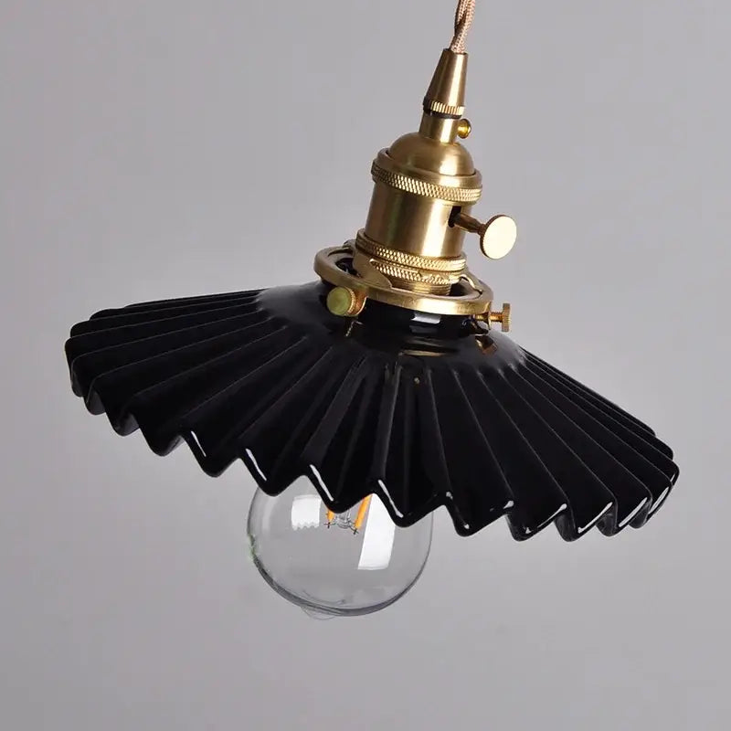 Modern black ceramic led pendant light with brass detail featuring a fan-shaped design and exposed bulb by decorbites