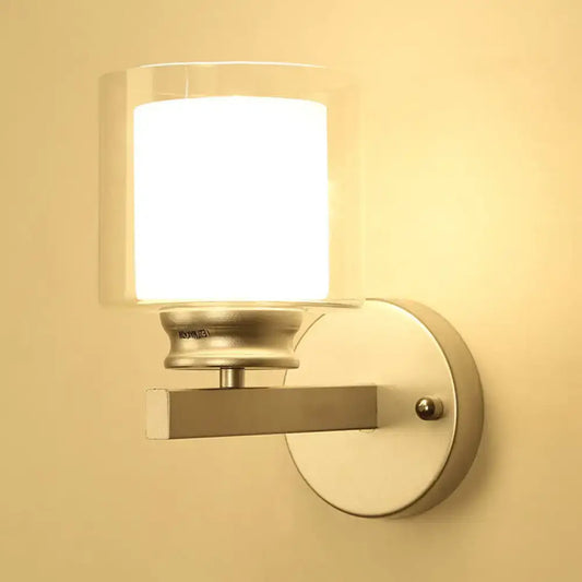Modern black and chrome wall mounted clear glass sconce with cylindrical shade for bedroom lighting