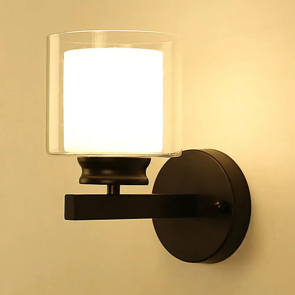 Modern black and chrome wall mounted clear glass sconce with illuminated white diffuser for bedroom lighting