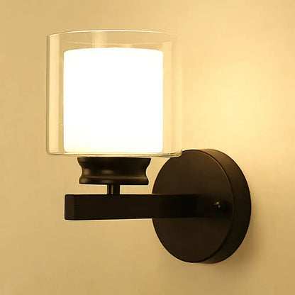 Modern black and chrome wall mounted clear glass sconce with illuminated white diffuser for bedroom lighting