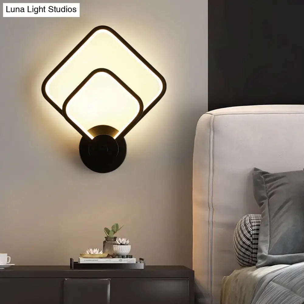 Modern black circular led light fixture wall sconce with overlapping square panels emitting warm glow for bedroom use