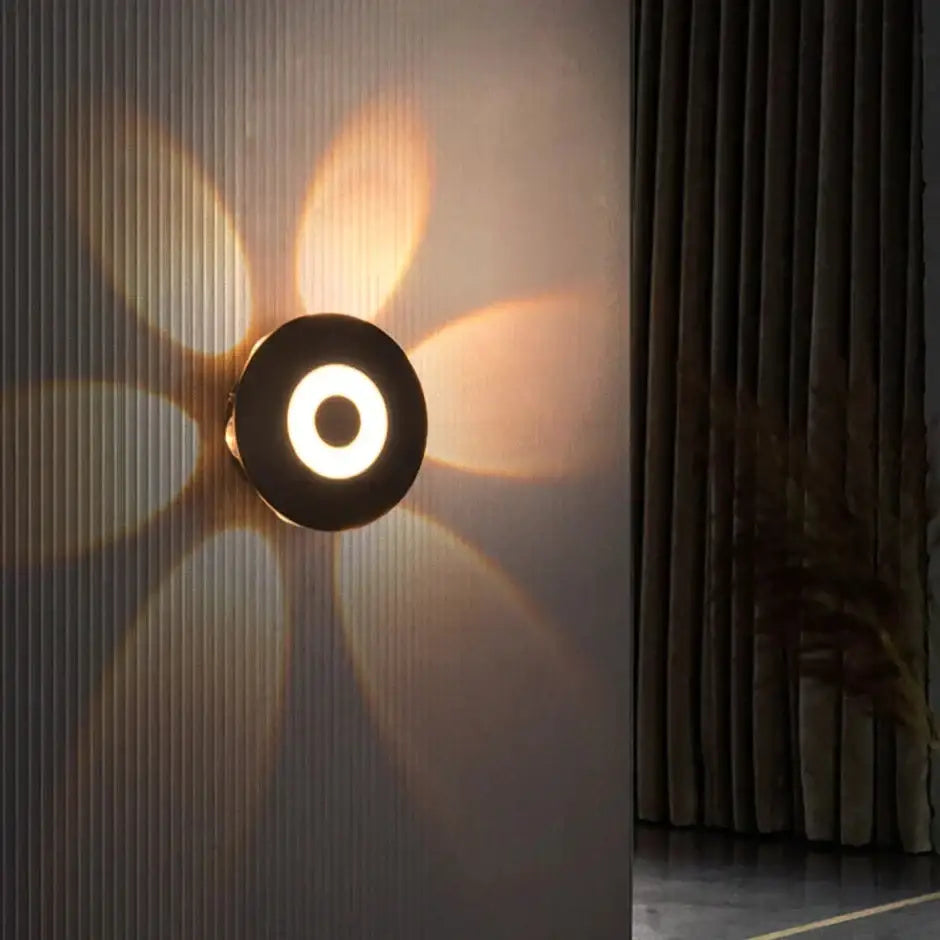 Modern black circular led outdoor wall sconce with glowing ring and radiating light beams for outdoor wall use