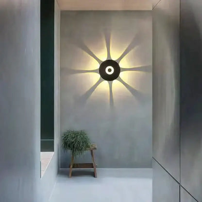 Modern black circular led outdoor wall sconce casting warm radiating light beams for garden outdoor wall lighting