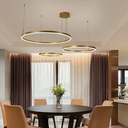 Modern gold-toned circular decorbites led pendant lights with minimalist design hanging above dining table