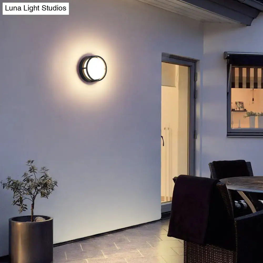 Modern black circular led wall lamp with sleek metal frame and frosted glass diffuser emitting warm color light for outdoor use