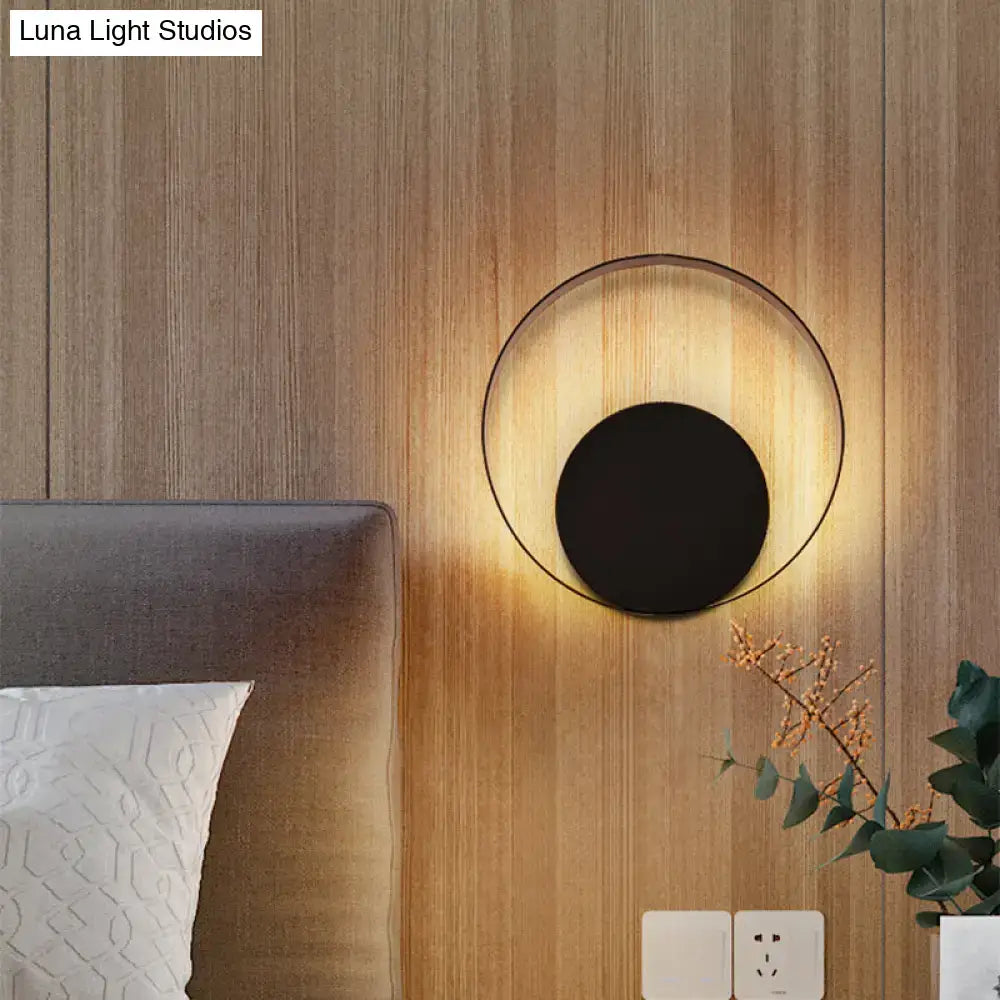 Modern black circular led wall sconce light fixture with sleek metallic ring and warm light type 10 inches high against wood panel