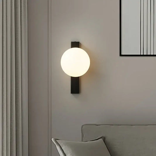 Modern black copper globe led wall sconce with frosted glass globe designed as a bedroom led wall light