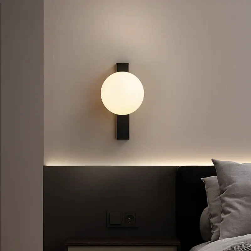 Modern black copper globe led wall sconce with frosted glass globe designed as a bedroom led wall light
