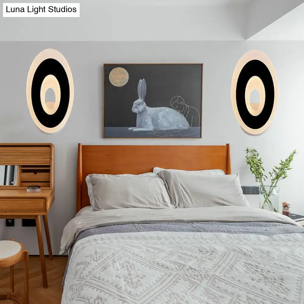 Modern black and cream oval direct wired electric wall lamp with sleek circular design and soft ambient light type for bedroom