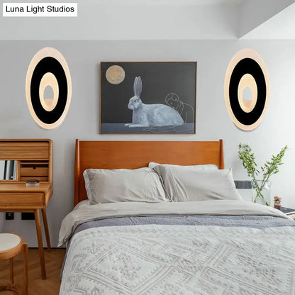 Modern black and cream oval direct wired electric wall lamp with sleek circular design and soft ambient light type for bedroom