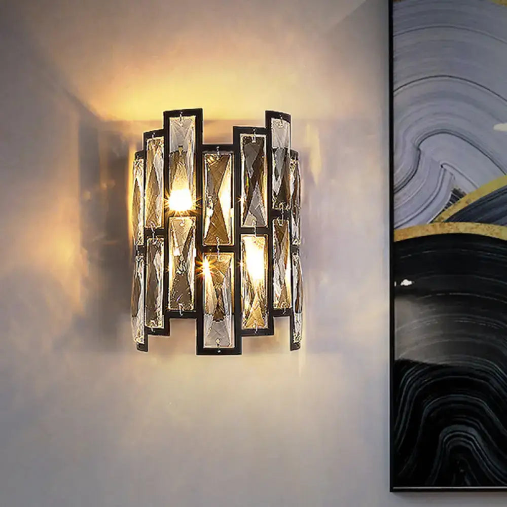 Modern black crystal half cylinder wall lamp with vertical rectangular panels in a sleek frame emitting warm light