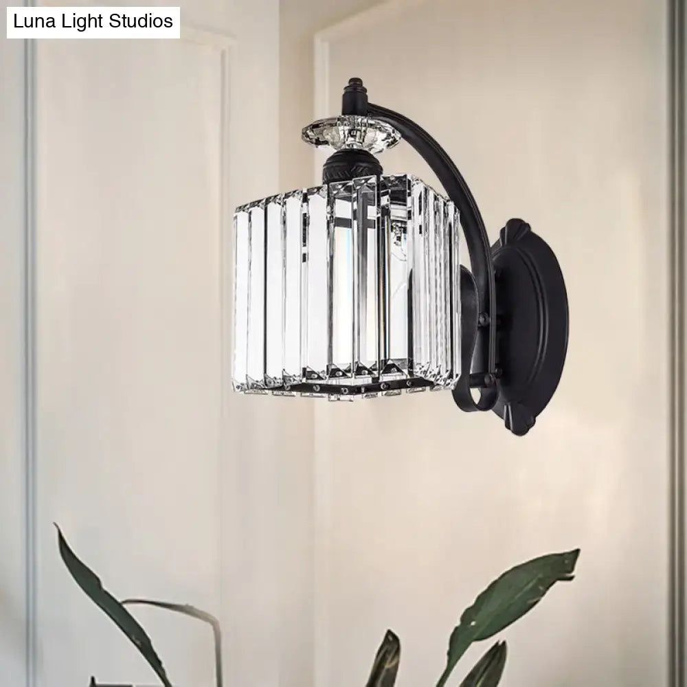 Black wrought iron wall light with clear faceted crystal cage and modern style curved arm for living room use