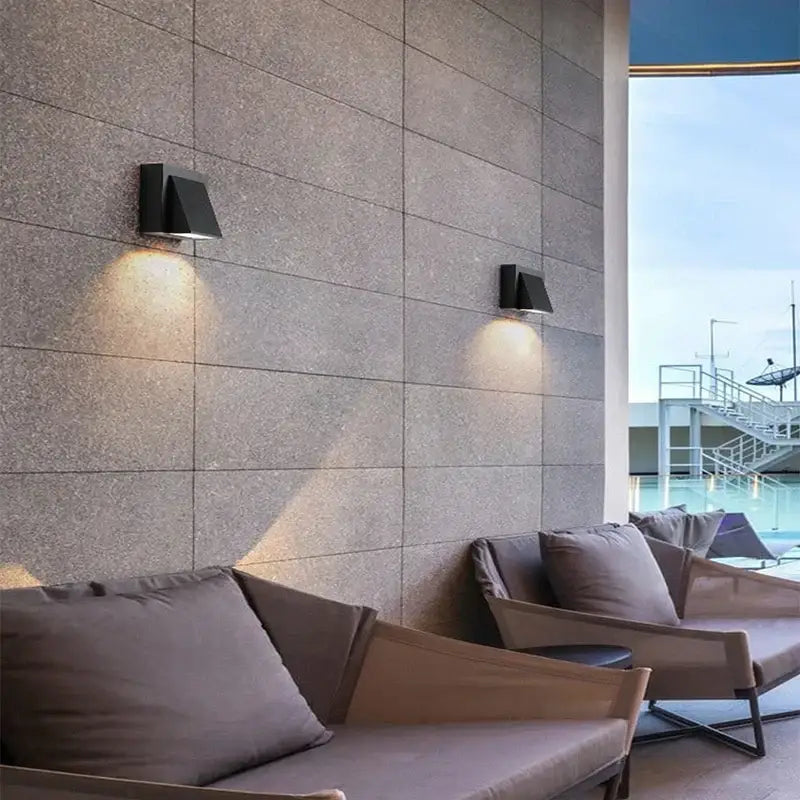 Modern black cube motion sensor led wall lamp casting warm light on textured stone wall for outdoor use