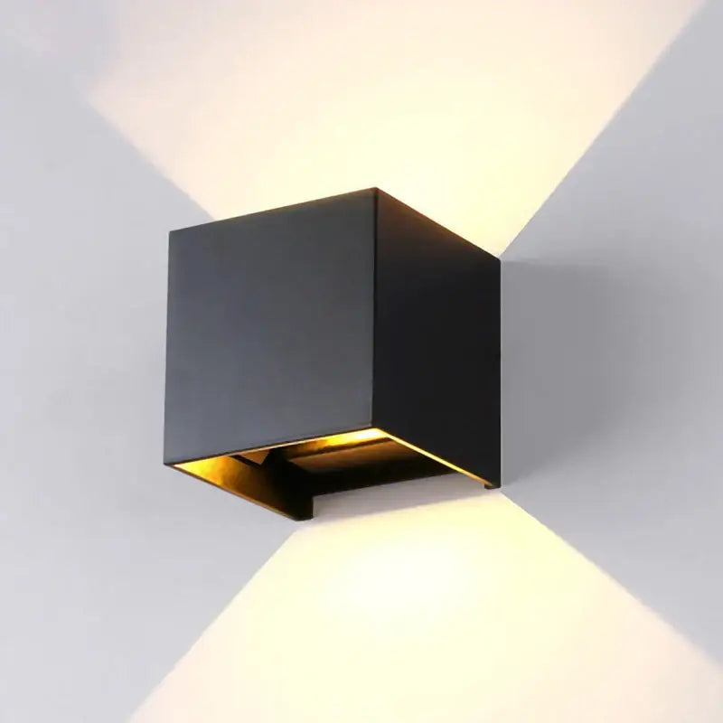 Modern black cube motion sensor led wall lamp with gold interior lining emitting warm light in two beams