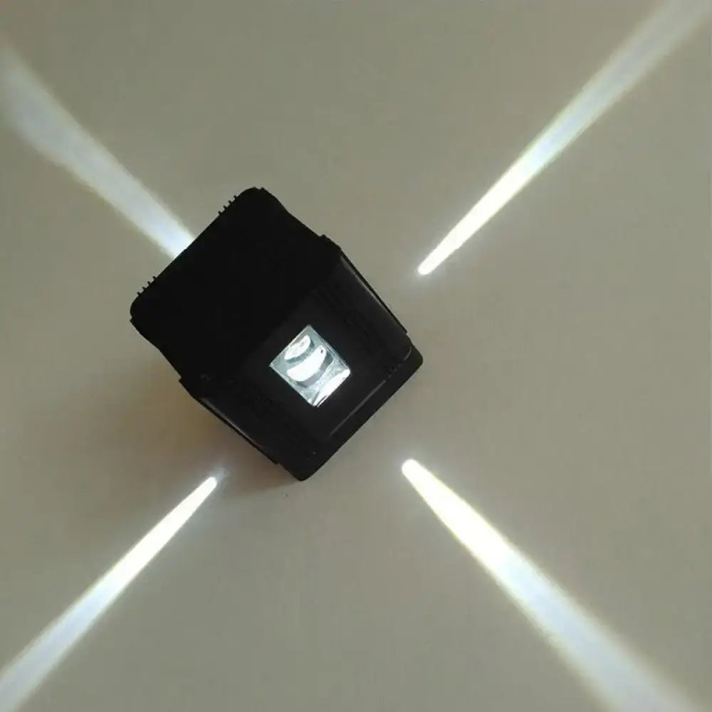Modern black cubic led wall lamp with a central illuminated panel casting four bright beams for bedroom lighting