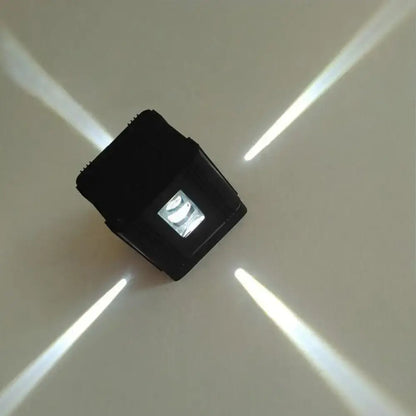 Modern black cubic led wall lamp with a central illuminated panel casting four bright beams for bedroom lighting