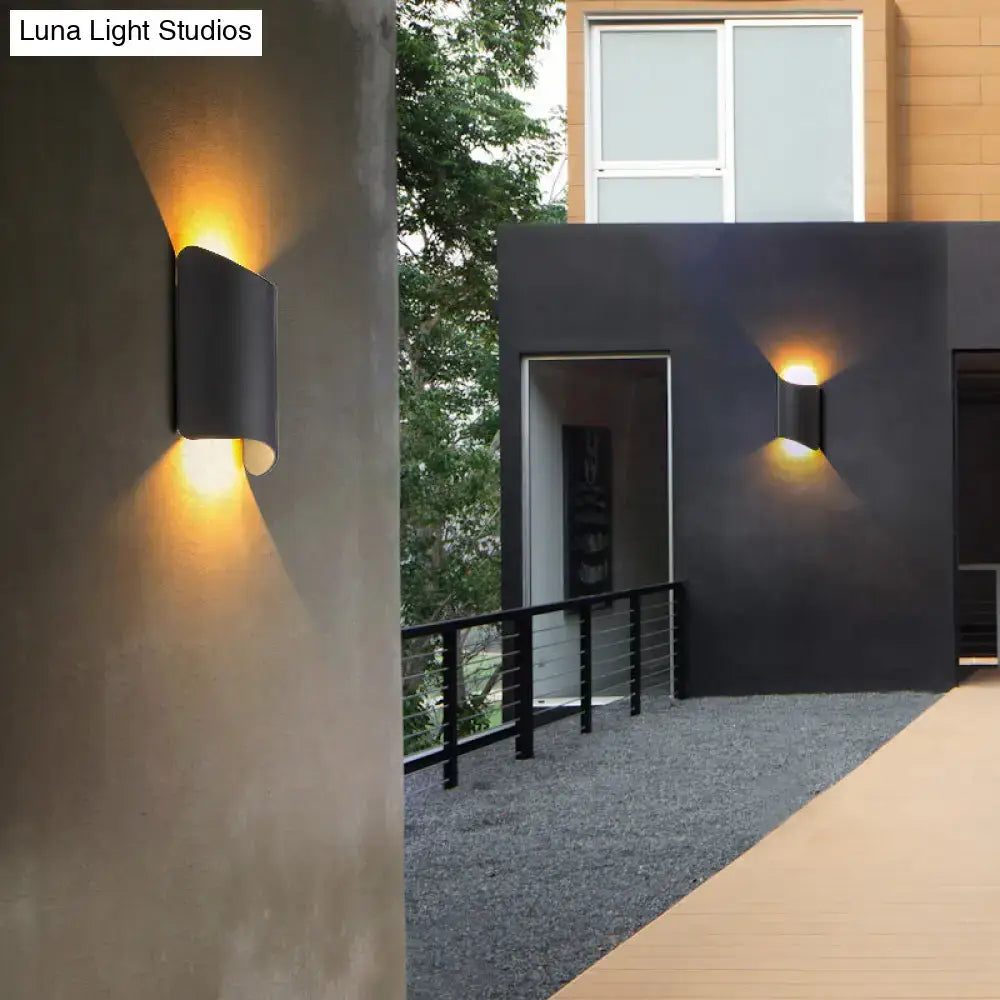 Modern black curved led wall lamp with sleek cylindrical design emitting warm yellow light for outdoor use
