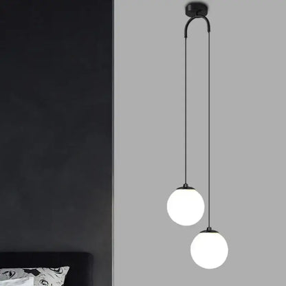 Modern black double glass ball pendant light featuring two frosted glass globes on a curved arm for bedroom ceiling