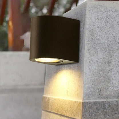 Modern black geometric led outdoor wall mount featuring a black cylindrical outdoor wall sconce with warm focused light