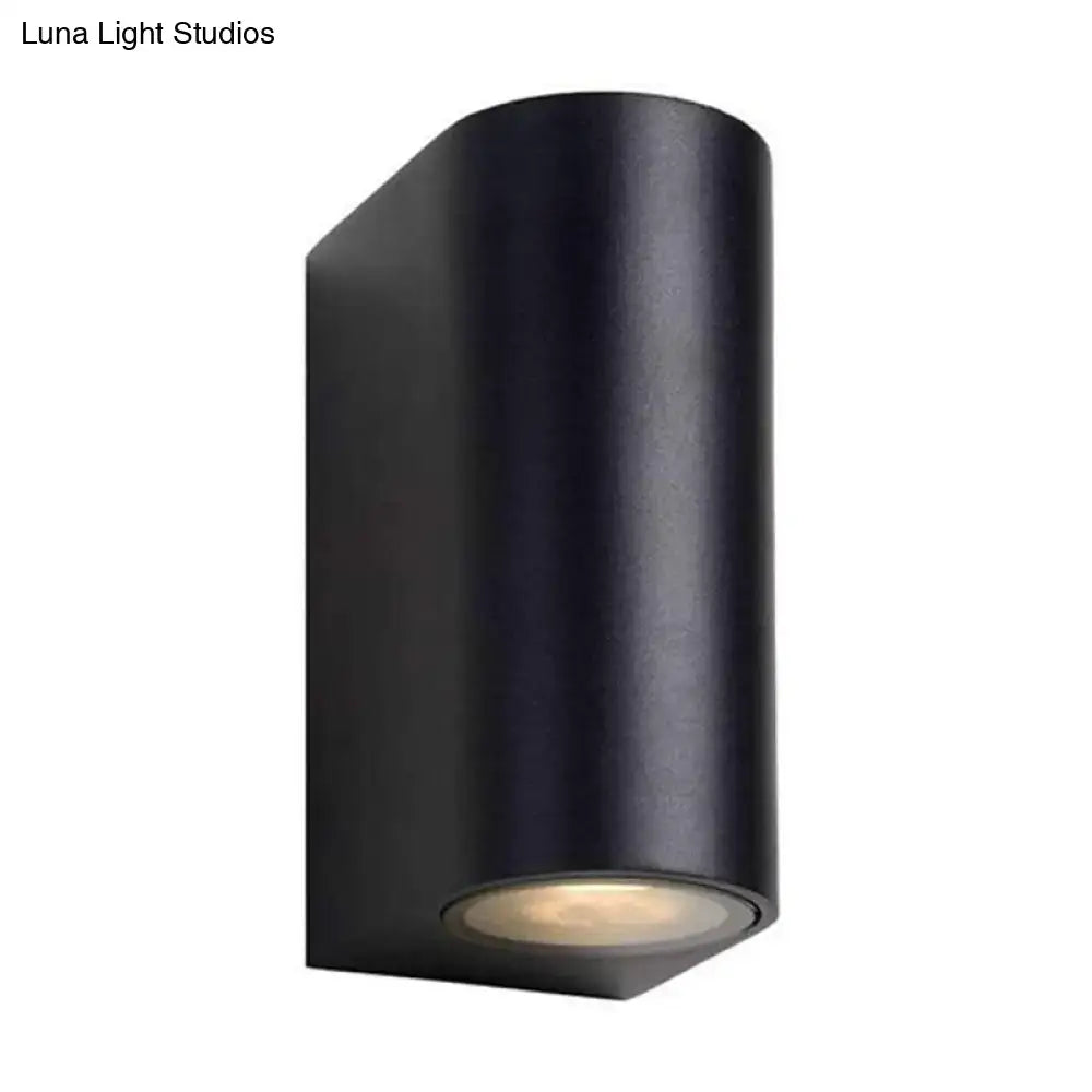 Modern black geometric led outdoor wall mount featuring a matte finish black cylindrical outdoor wall sconce with warm led light at the base