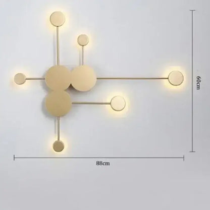 Modern gold-toned wall lamp with geometric interconnected circular design and warm ambient led lighting for bedroom minimalism