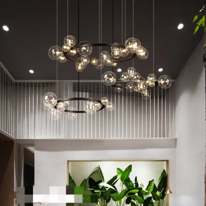 Modern black glass globe pendant light fixture with black metal rings and hanging wires for dining room lighting