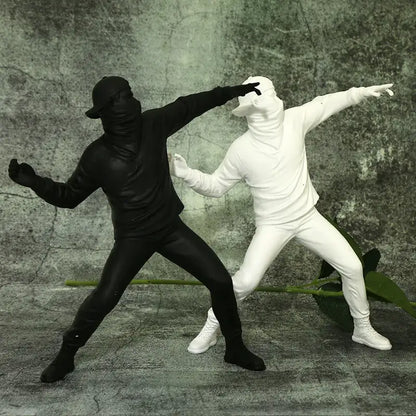 Modern black glossy bansky flower thrower sculpture featuring black and white plastic figurines in dynamic poses