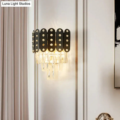 Modern black and gold 3-tiered wall-mounted light with clear faceted crystal droplets and gold-toned studs for living rooms