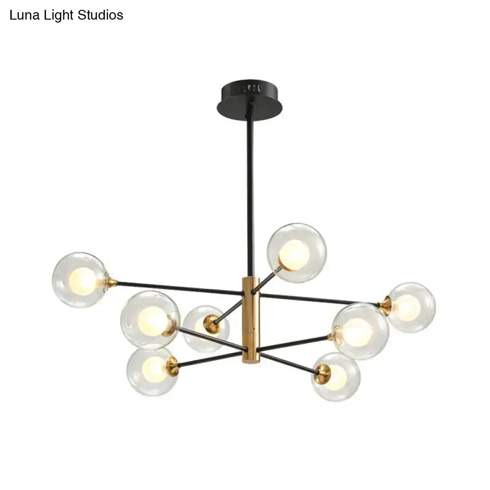 Modern chandelier with brass central fixture black metal arms and clear glass globes offers elegant living room lighting with fixture width