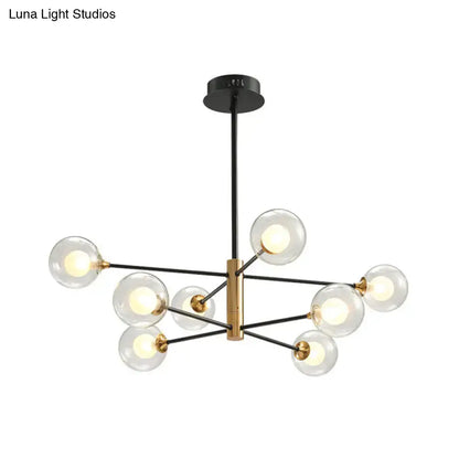 Modern chandelier with brass central fixture black metal arms and clear glass globes offers elegant living room lighting with fixture width