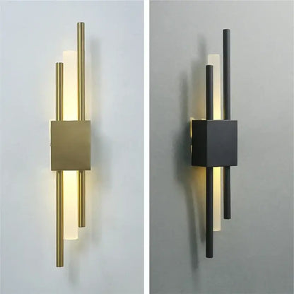 Modern black and gold acrylic pipe wall lamp with brushed brass base and frosted glass diffusers emitting warm light