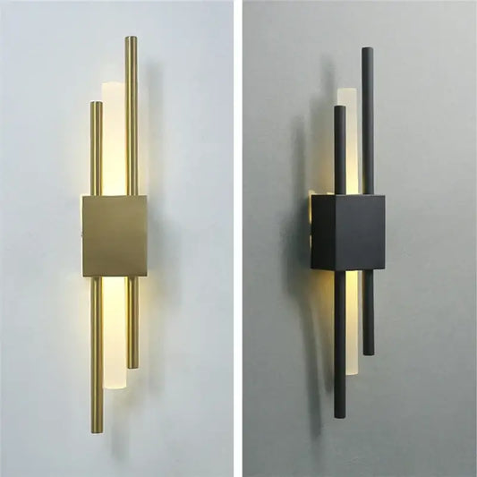 Modern black and gold acrylic pipe wall lamp with brushed brass base and frosted glass diffusers emitting warm light
