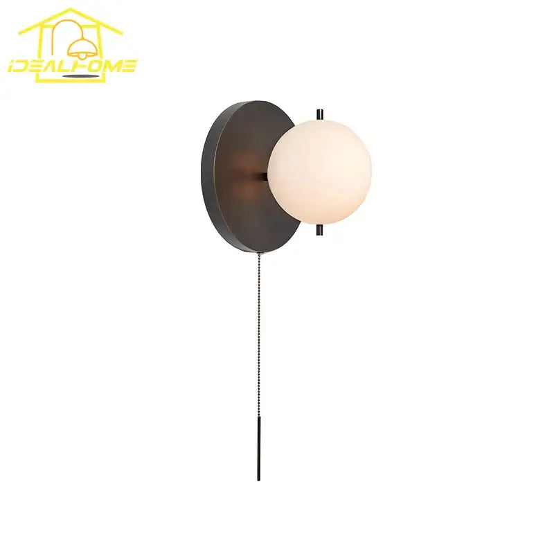 Modern black gold ball wall lamp with a matte circular base and off-white glass globe for bedroom decorbites black gold