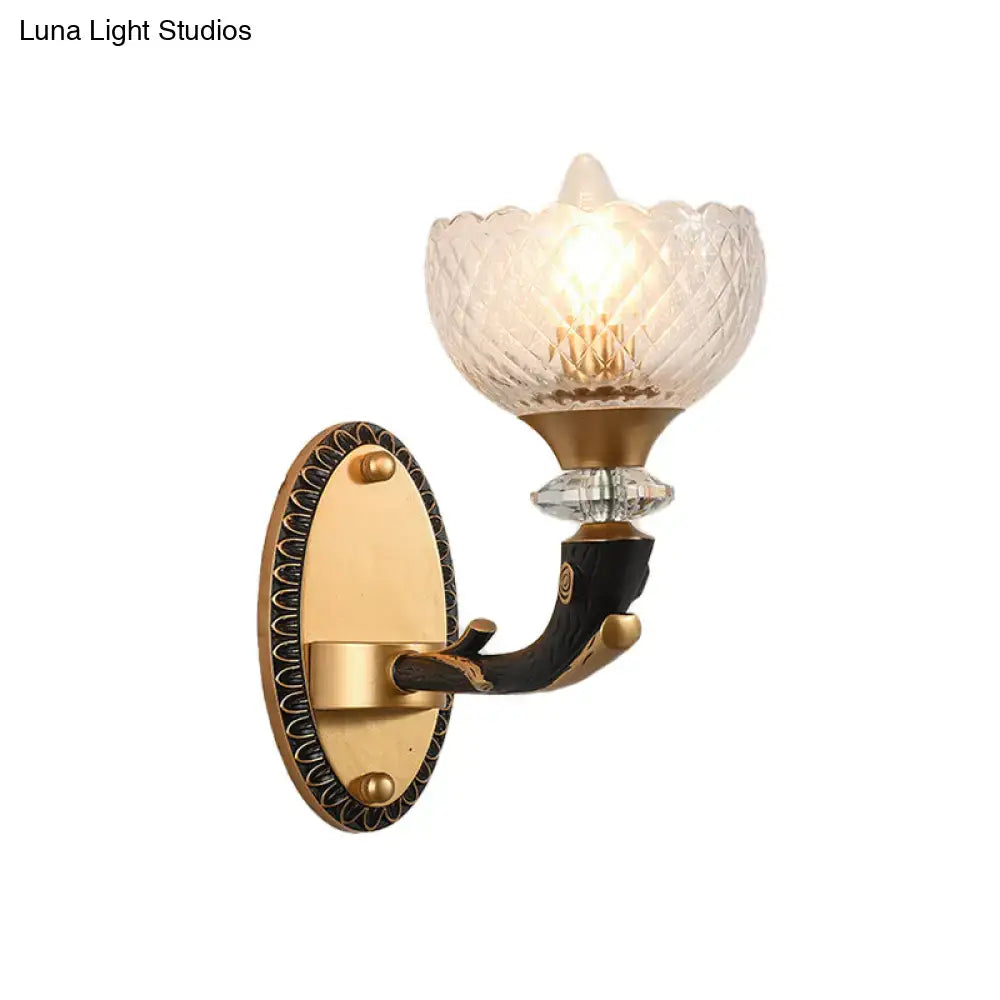 Modern black and gold metal black sconce with clear prismatic glass shade on antique brass and black lacquered wood base