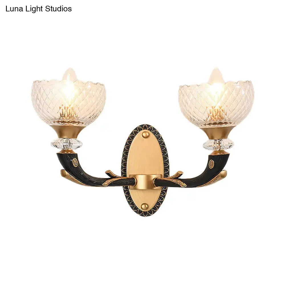 Elegant metal black sconce with gold accents and clear prismatic glass shade for modern bedroom lighting