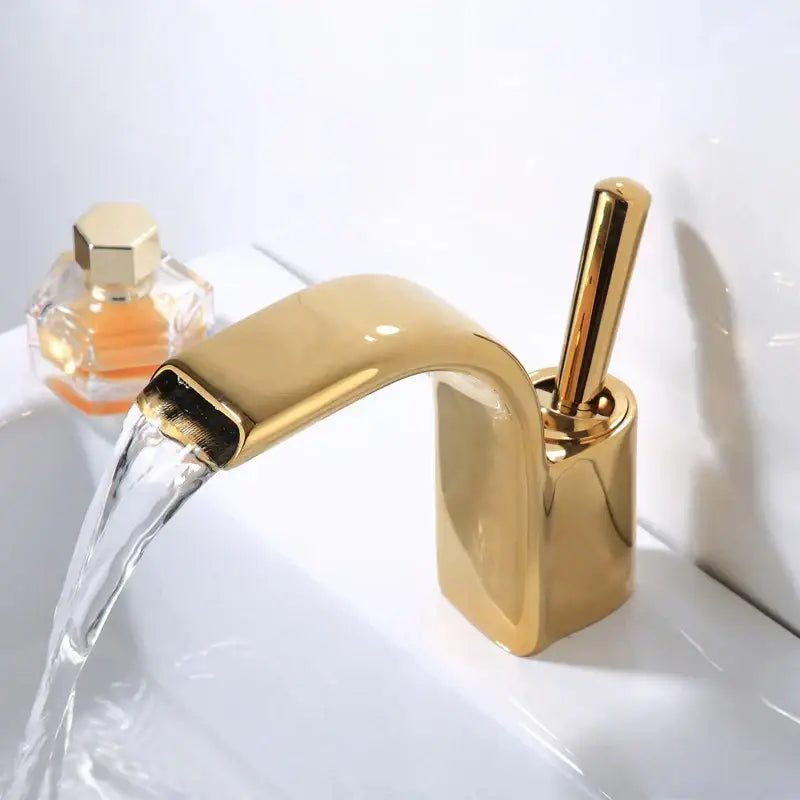 Modern black and gold brass waterfall basin faucet with gold-toned curved spout and rectangular base by decorbites black brass