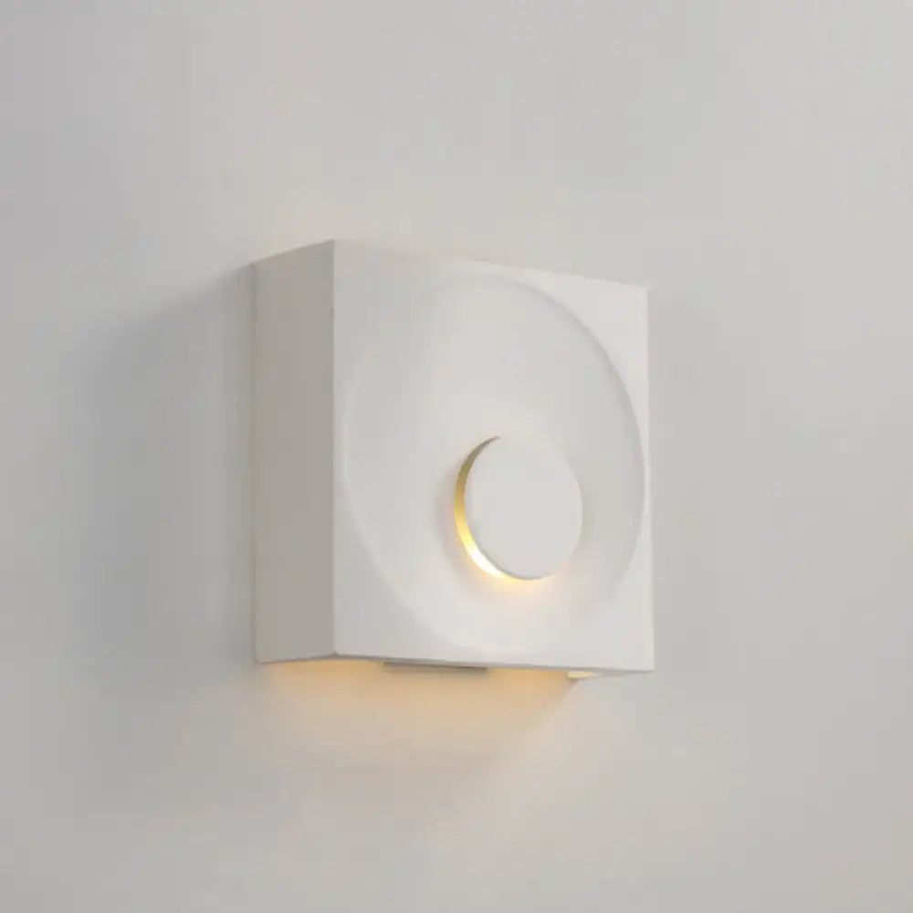 Modern black and gold cement square wall light with minimalist circular cutout emits warm ambient light type for bedroom