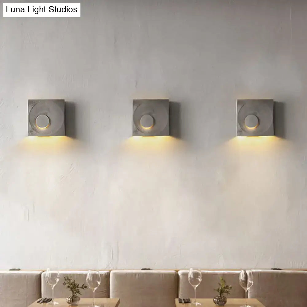 Modern black and gold cement square wall light with circular cutouts emitting warm ambient light type for bedroom use